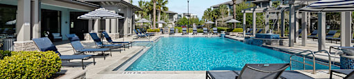 A pool surrounded by lounge chairs and umbrellas.