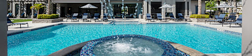 A blue tiled hot tub sits in the middle of a pool.