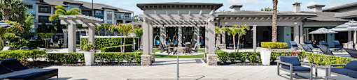 A pool area with a small pool, lounge chairs, and a building in the background.