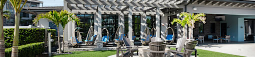 A patio area with a white pergola and several chairs.