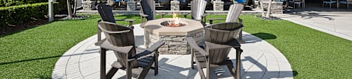 A patio with a fire pit and chairs.