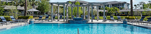A large swimming pool surrounded by lounge chairs and palm trees.
