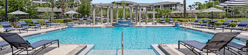 A large swimming pool surrounded by lounge chairs and palm trees.