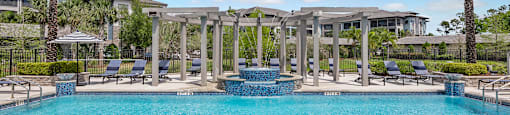 A large swimming pool surrounded by palm trees and lounge chairs.