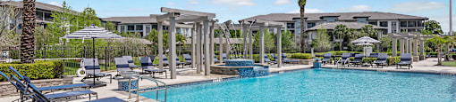 A pool with sun loungers and palm trees.