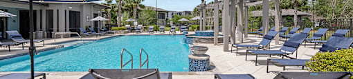 A pool area with lounge chairs and a wooden structure.