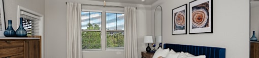 A bedroom with a bed, dresser, and ceiling fan.
