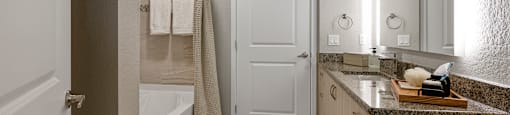 A bathroom with a white door, a white tub, and a rug on the floor.