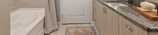 A bathroom with a white door, a white tub, and a white shower curtain.