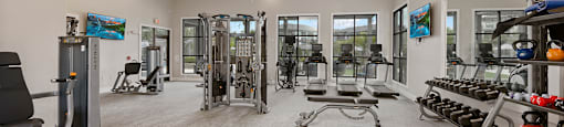 A gym with a variety of equipment including treadmills, weights, and exercise machines.
