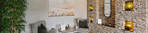A living room with a stone wall and a painting on the wall.