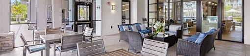 A wooden table is surrounded by chairs in a room with a glass wall.