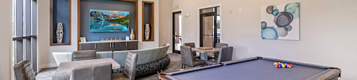 A pool table is in the middle of a room with a couch and chairs.