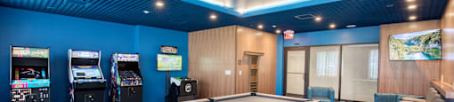 A room with a pool table and arcade games.