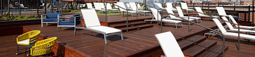 A rooftop patio with white chairs and umbrellas.