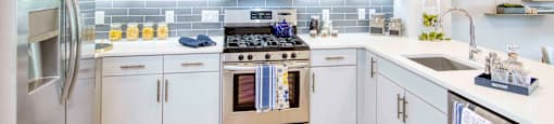 a modern kitchen with white cabinets and stainless steel appliances at The Enclave, Jersey City, NJ