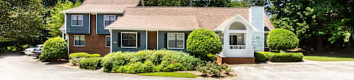 a house with a driveway and trees in the background