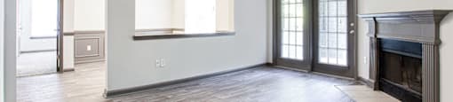 an empty living room with a fireplace and french doors