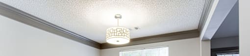 an empty dining room with gray walls and a chandelier