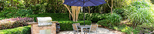 a patio with a grill and a table and chairs
