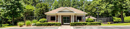 a parking lot in front of a brick building with trees in the background