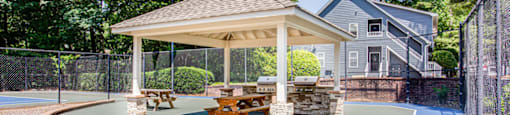 a backyard tennis court with a pavilion and picnic table