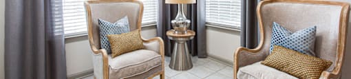 a seating area with two chairs and a table with a lamp