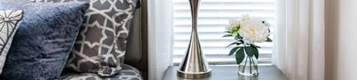 a bedside table with a lamp and a vase of flowers on it