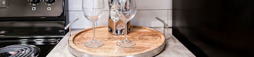a bottle of wine and two wine glasses on a wooden board in a kitchen