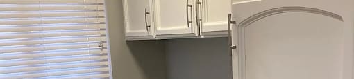 A kitchen with white cabinets and a white refrigerator.