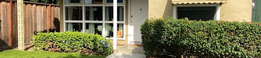 a small tan house with a sidewalk and lawn