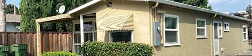 a small yellow house with a driveway and a yard