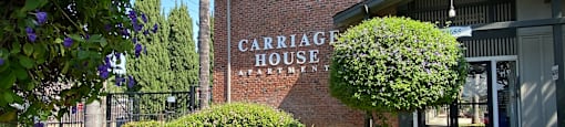 a sidewalk in front of a building with a sign that reads carriage house