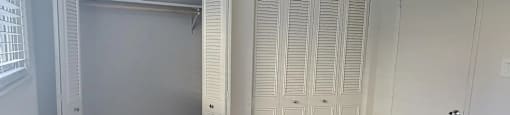 A room with a white door, a white wardrobe, and a white closet.