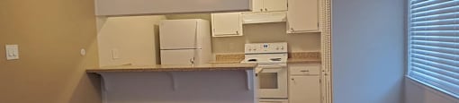 A kitchen with a fan on the ceiling and wooden floors.