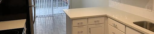 A kitchen with white cabinets and a black fridge.