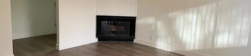A room with a fireplace and wood flooring.