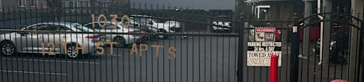 A parking lot with a sign that says "10:30 ST APTS" and a black fence.