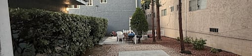 A gravel courtyard with a tree and a building in the background.
