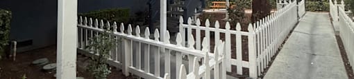 A house with a white picket fence and a staircase leading to the second floor.