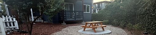 A modern building with a balcony and a picnic table in front.
