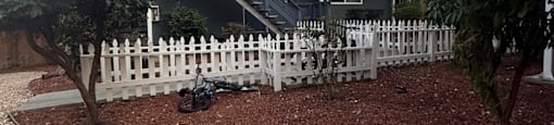 A modern house with a white picket fence and a bicycle leaning against it.