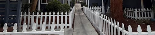 A white picket fence runs down the middle of a tree-lined street.