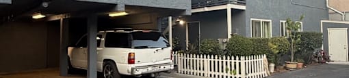 A car is parked in a garage attached to a grey building.