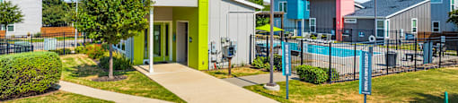A brightly colored building with a green door is surrounded by a well-kept lawn and a clear blue sky.