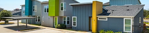 A row of modern houses with a parking lot in front.
