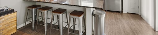 A kitchen with a refrigerator, stove, and bar stools.