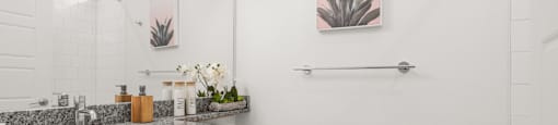 A bathroom with a toilet, sink, and a picture of a plant on the wall.