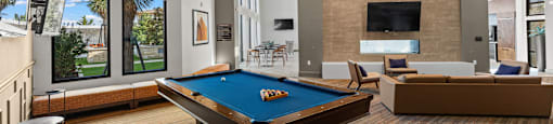 A pool table is in the middle of a room with a couch and a television.