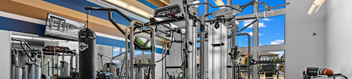 A gym with a variety of equipment including a punching bag, weight machines, and a treadmill.